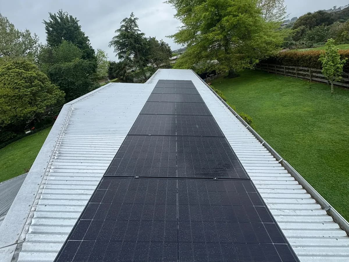 A 9.1kW EFS Solar array running up a metal roof at a Cambridge home, Waikato, with a large tree and lawn behind
