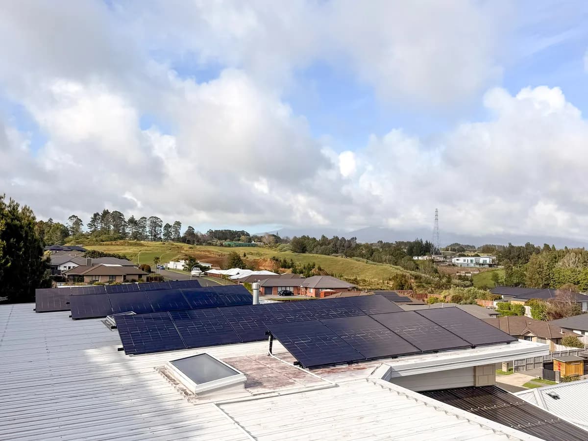 A 9.1kW EFS Solar array on a low metal roof in New Plymouth, Taranaki, with a rural valley and hills behind