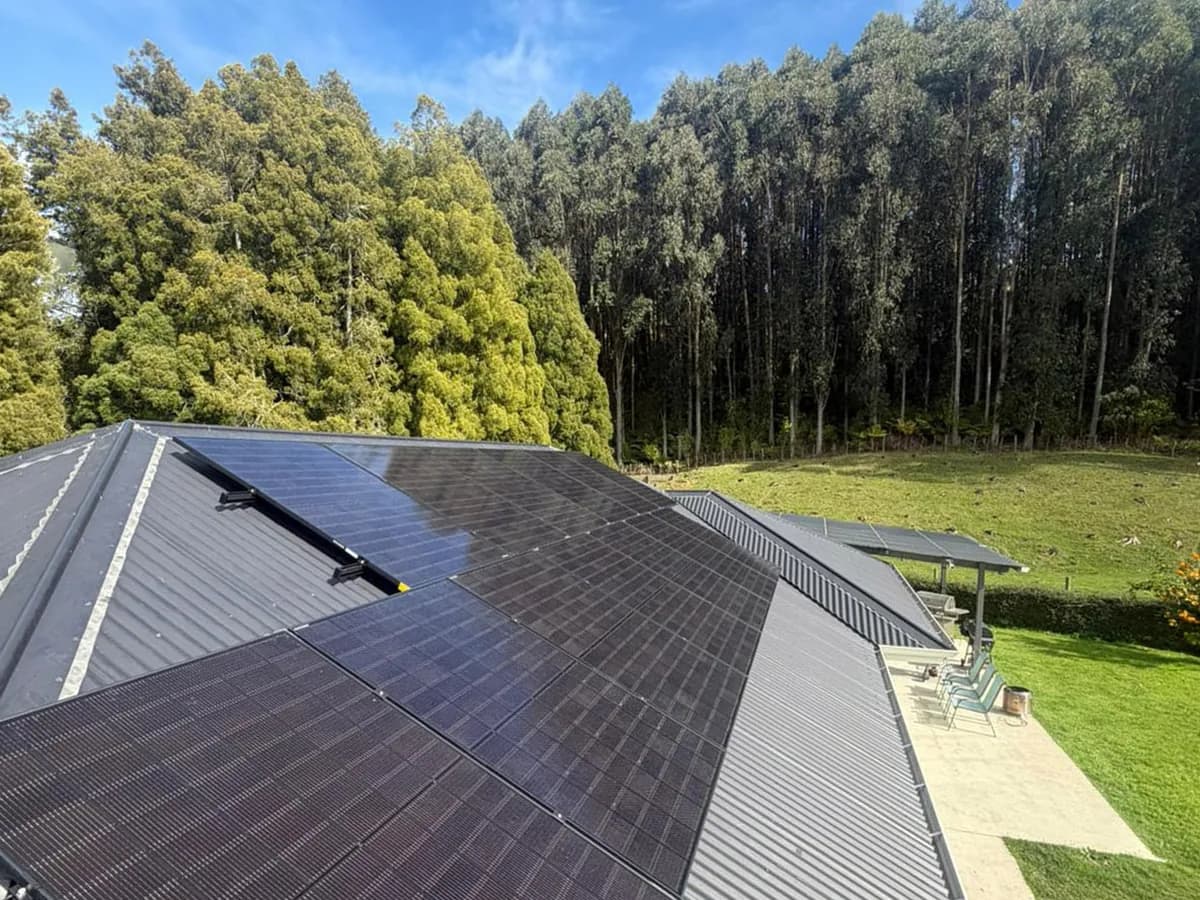 A 13.01kW EFS Solar array on the charcoal metal roof of a rural home at Ngāruawāhia, Waikato, gum trees behind