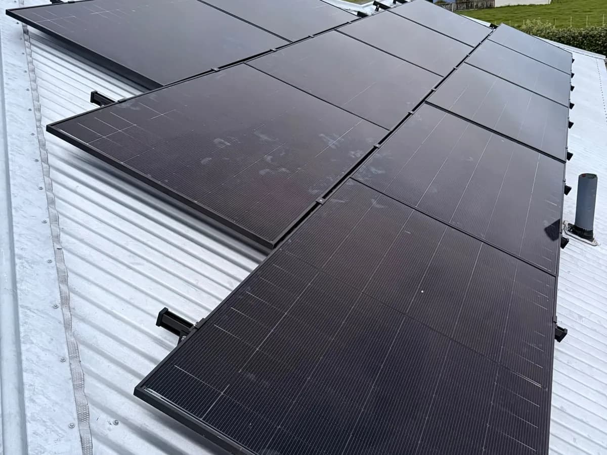 A 10.47kW EFS Solar array on a white metal roof at a rural Ōpunake home, South Taranaki, with paddocks behind