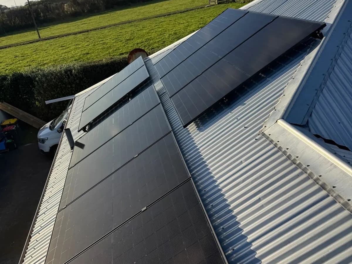 A 10.47kW EFS Solar array on a silver metal roof at a rural Ōpunake property, South Taranaki, green paddocks behind