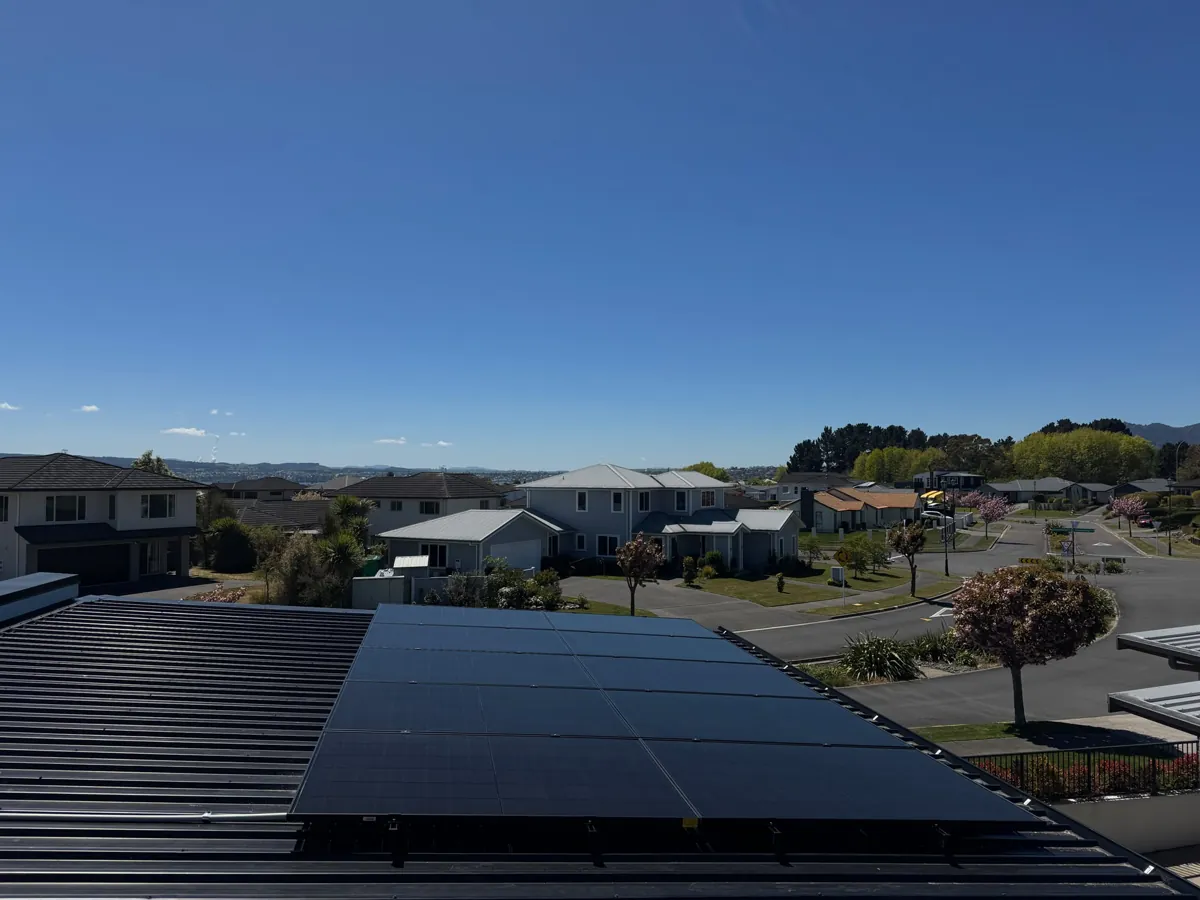A 10kW EFS Solar array on a charcoal metal roof in Taupō, Waikato, with the town and hills behind