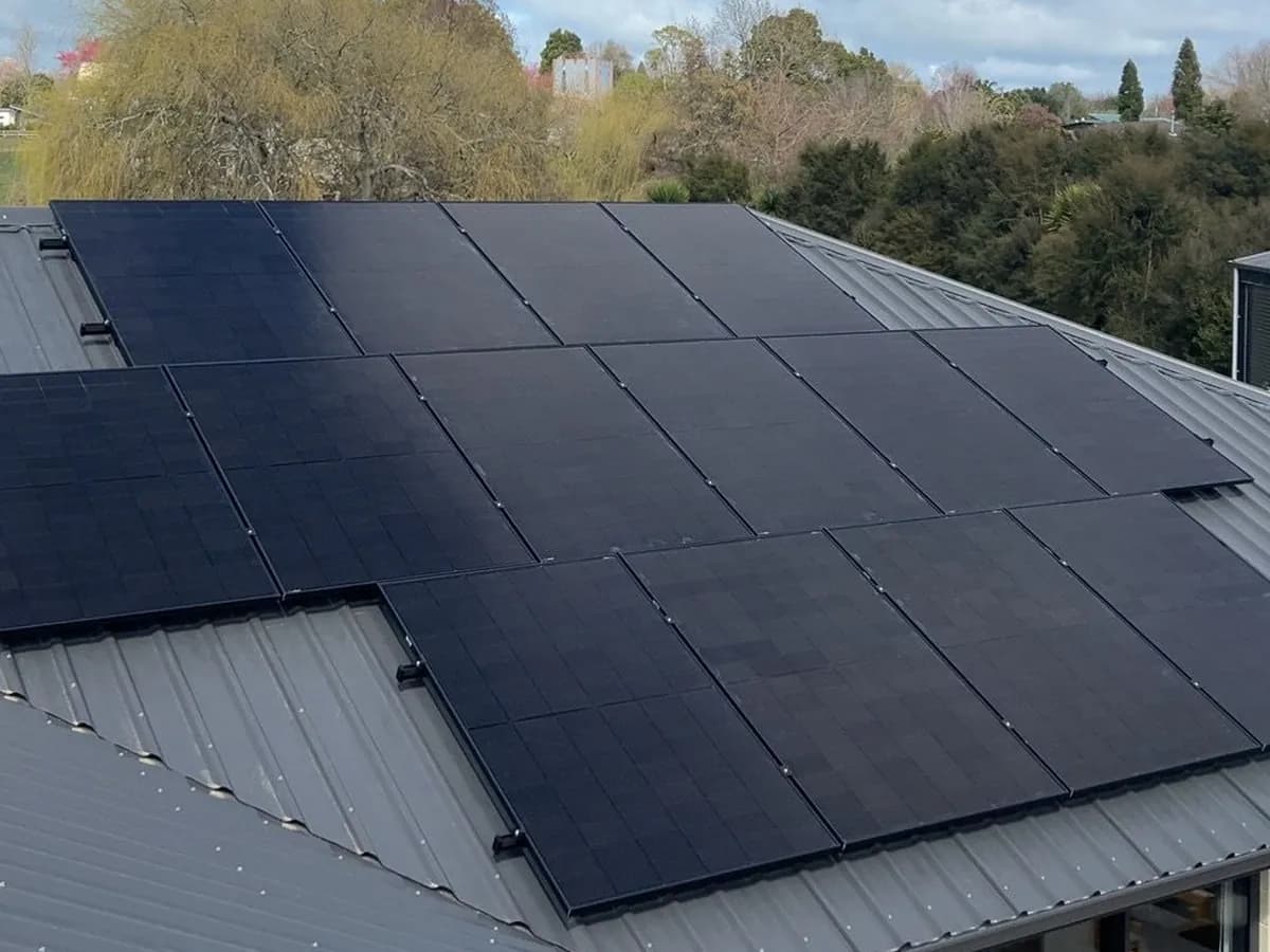 A 13.65kW EFS Solar array on a charcoal metal roof in Te Awamutu, Waikato, trees behind