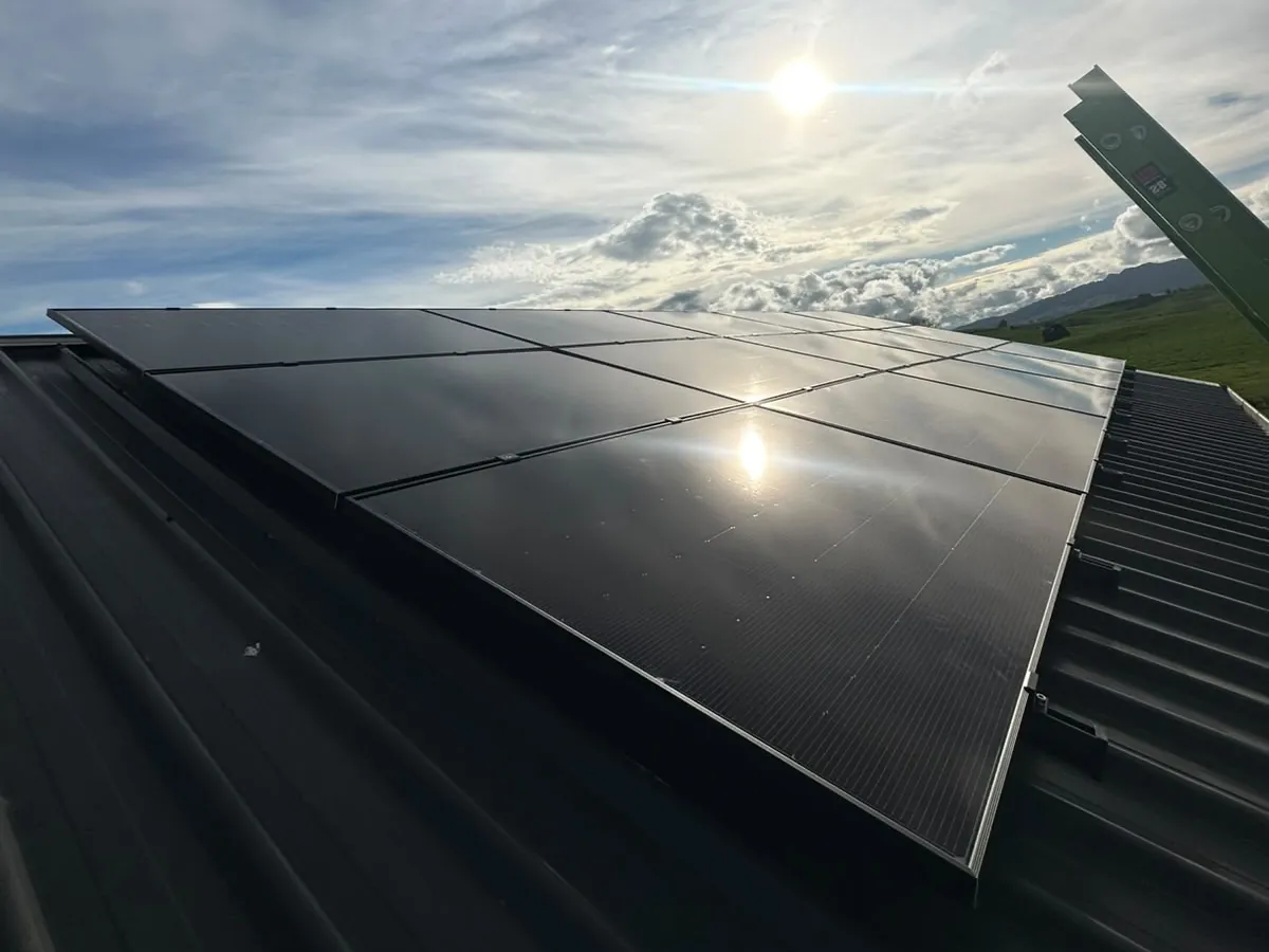 A 6.83kW EFS Solar array on a charcoal metal roof at a rural Waotu property, Waikato, with hills and a dramatic sky behind